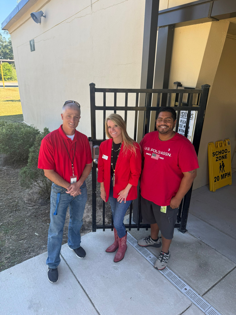 Mr. Harvell, Mrs. Windham, and Mr. Otto wear red and pose outside a school entrance to celebrate Red Ribbon Spirit Day and promote healthy, drug-free choices