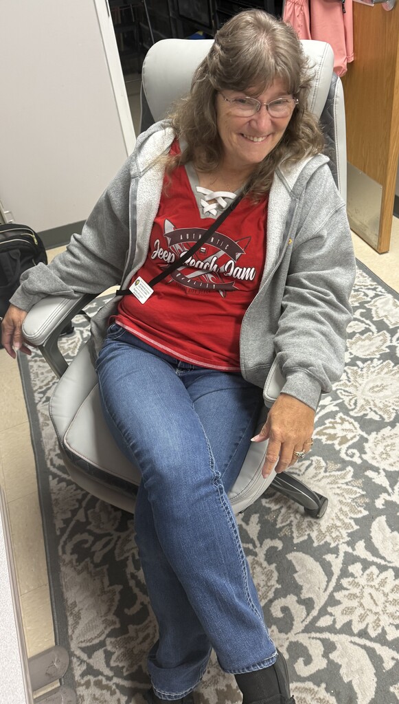 A staff member wearing red sits in an office chair to show support for Red Ribbon Spirit Day and the promotion of healthy, drug-free choices.