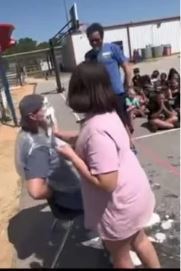 Teacher getting hit in the face by a student during Boosterthon 2025. Other students looking on.
