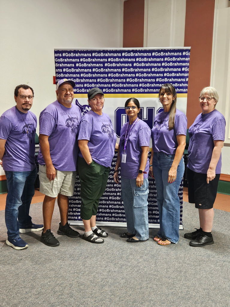 six teachers wearing purple shirt Infront of brahman backdrop