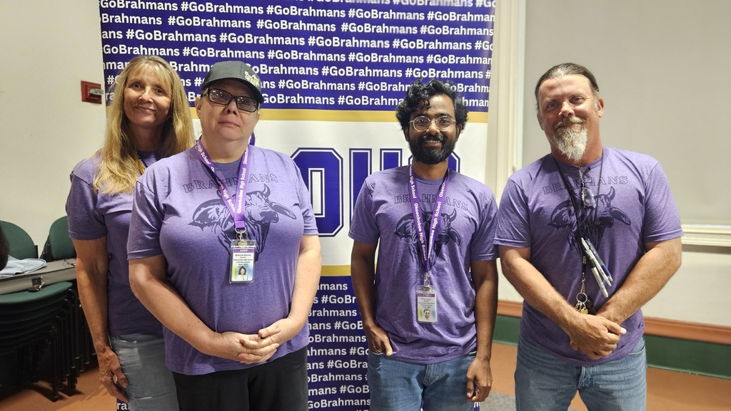 four science teachers wearing brahman purple shirt Infront of brahman backdrop