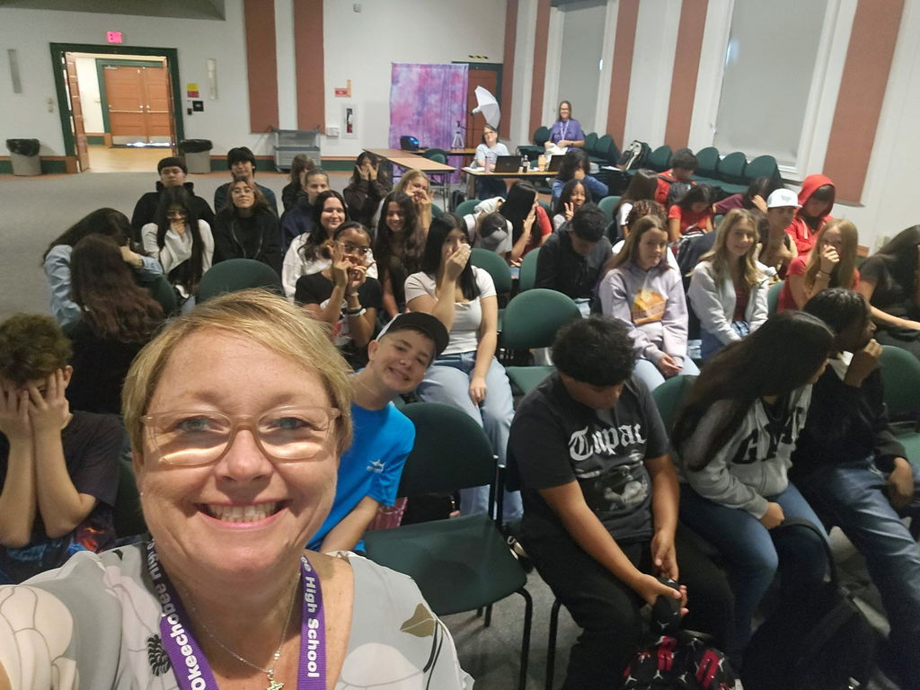 principal taking selfie with students in auditorium for town hall meeting