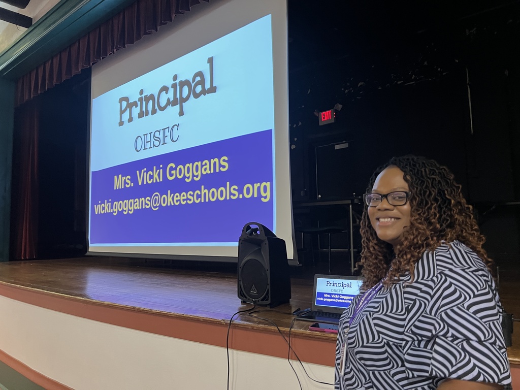 assistant principal smiling presenting town hall meeting by stage