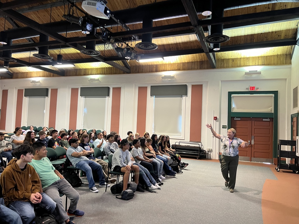 principal waving to students in town hall meetings in auditorium