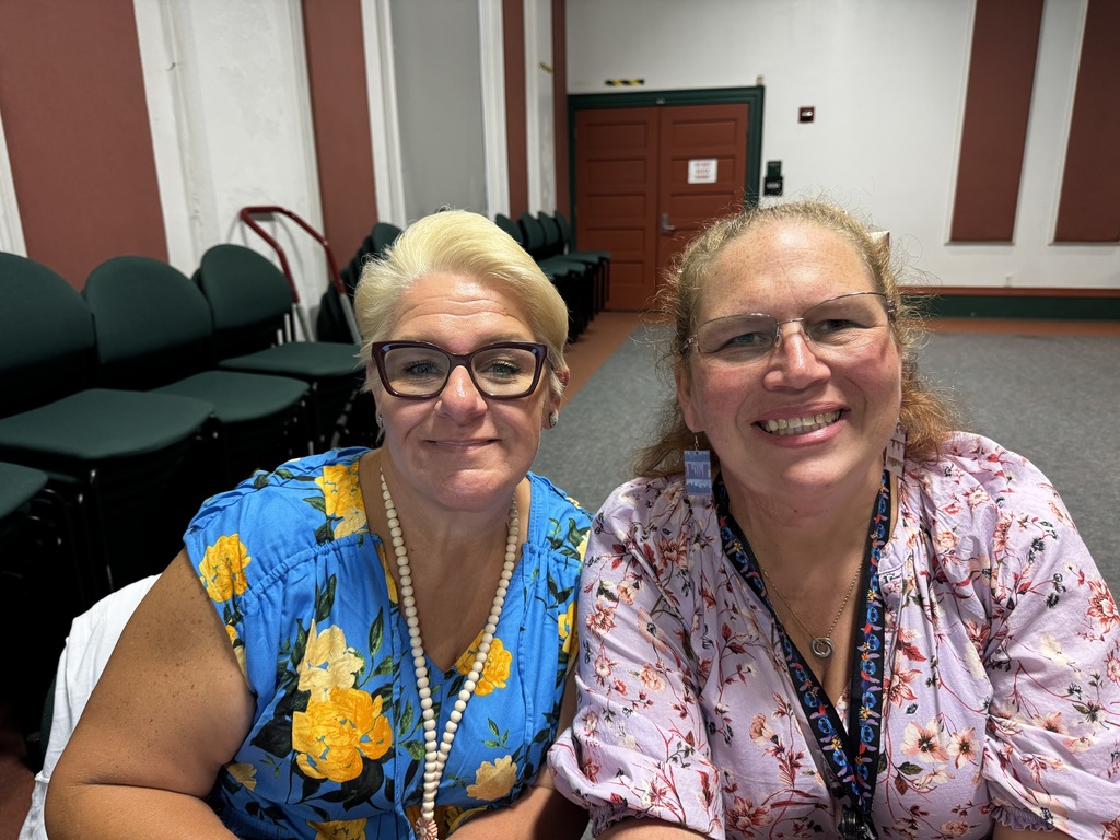 two teachers smiling in school auditorium