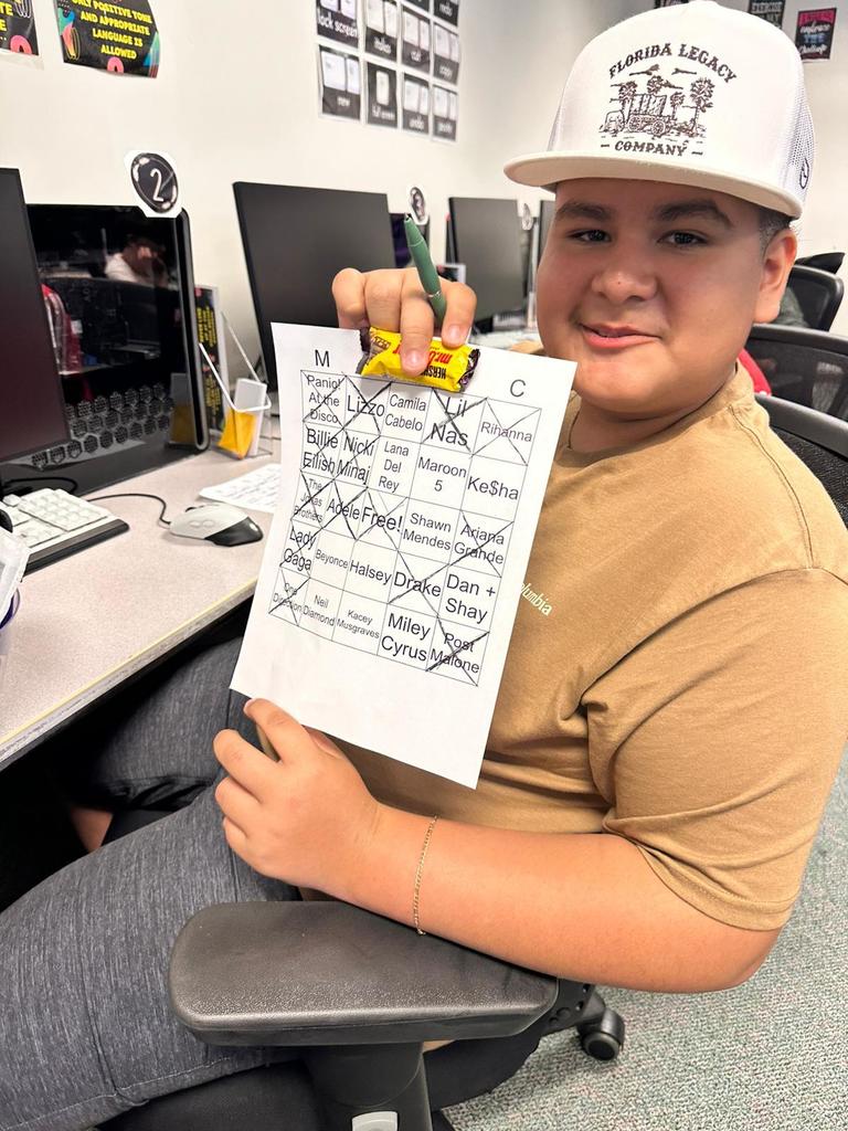 student sitting in digital tech class showing chocolate and paper
