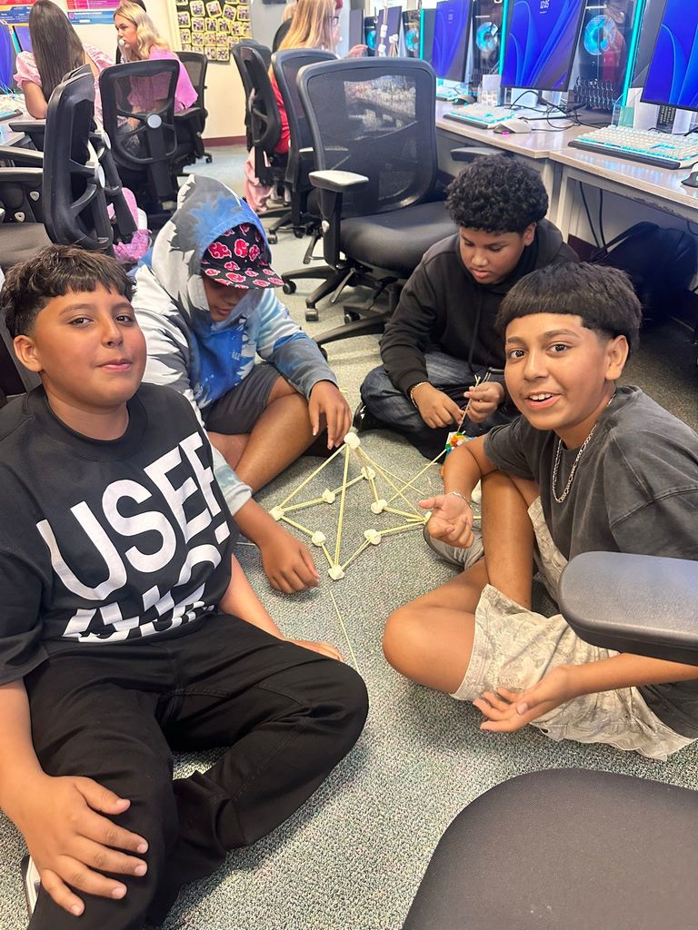 four students on floor doing marshmallow project in digital tech
