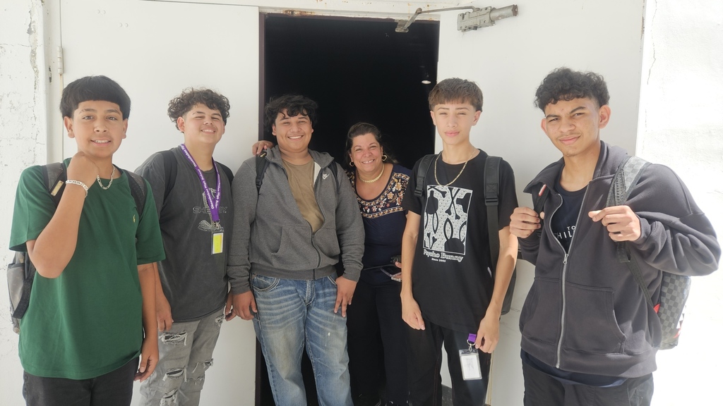 five students standing with custodian by gym door