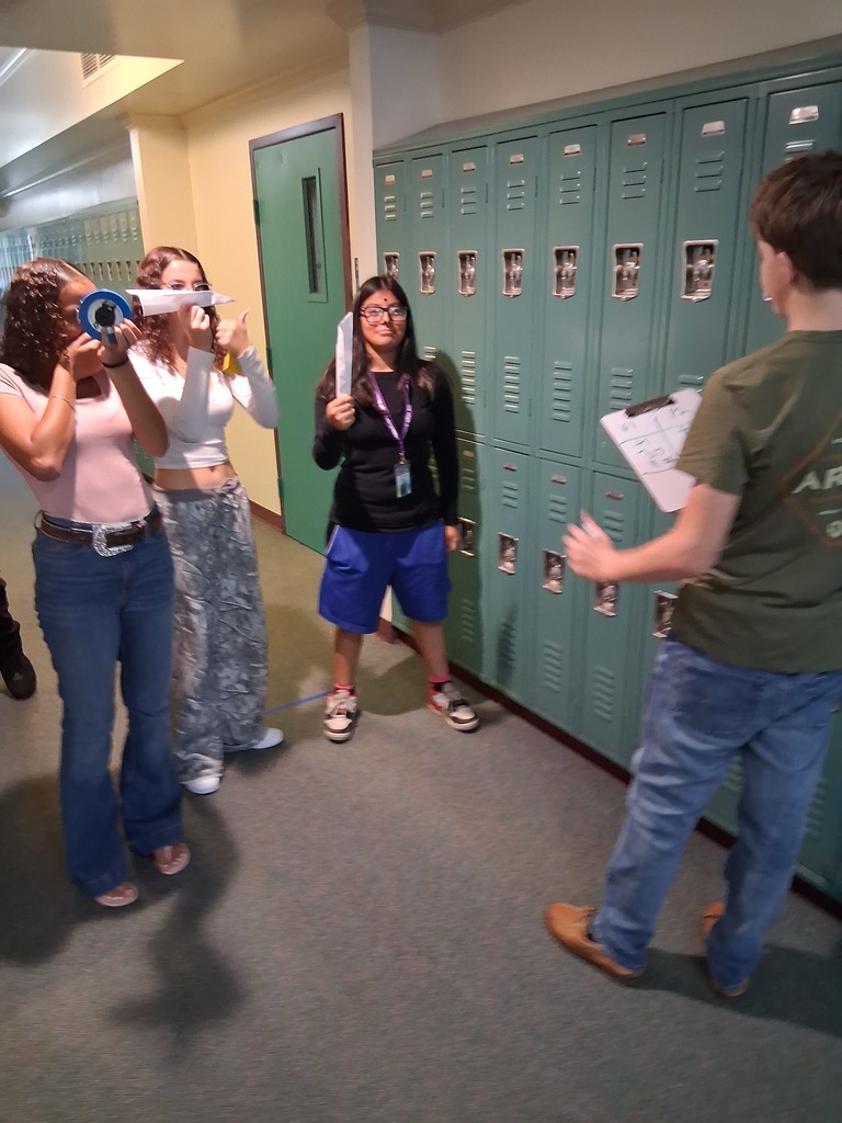 four students doing airplane project in hallway