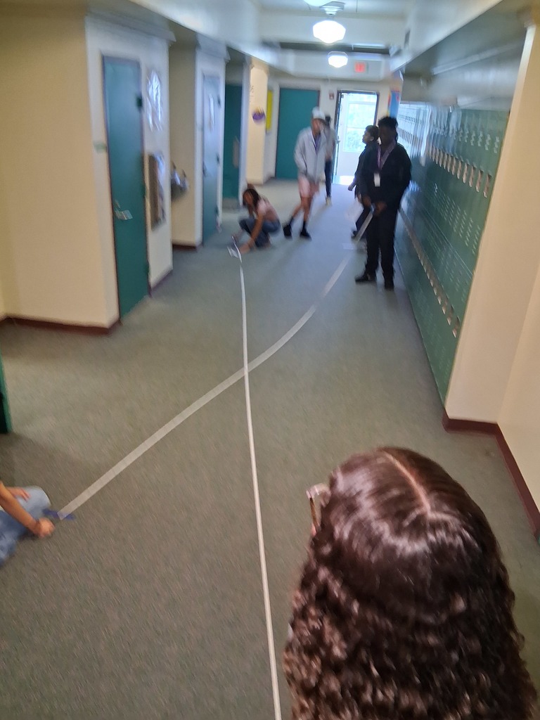 students holding two strings in hallway