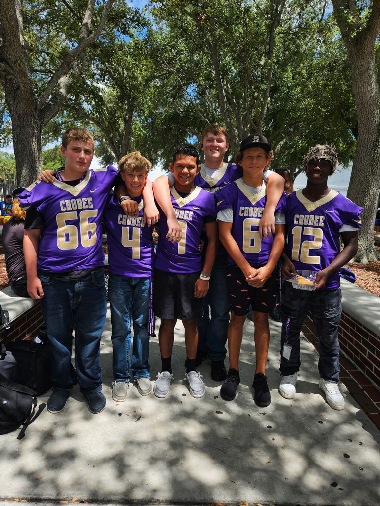 six students wearing football jerseys in courtyard