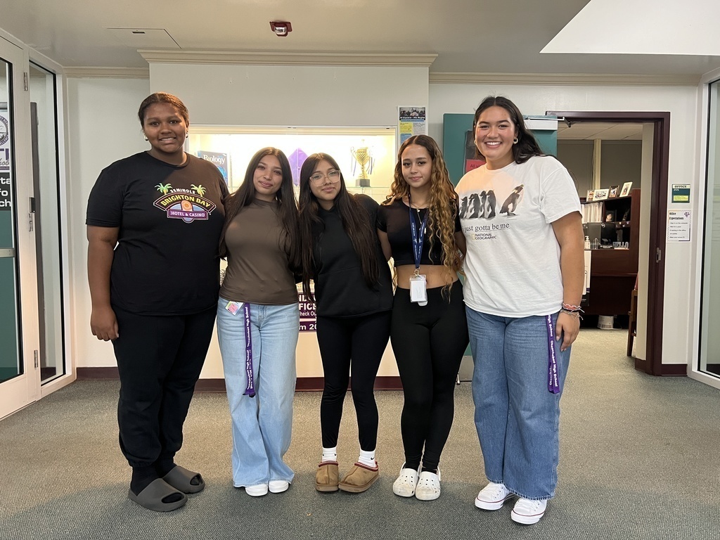 five students standing Infront of their school's main office