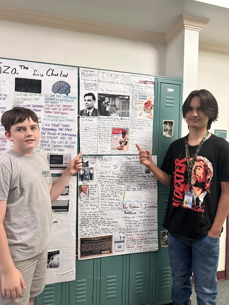 two students pointing to AI poster in hallway