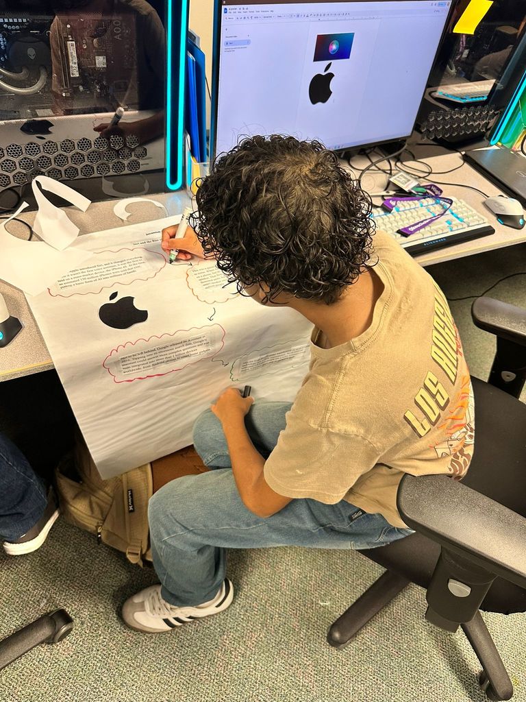 student working on AI poster Infront of computer in classroom