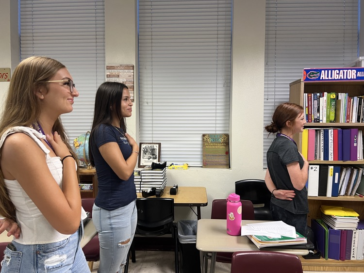 three girls pledging to the flag in biology room