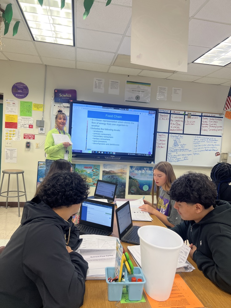 Science group and teacher smiling in the background of classroom