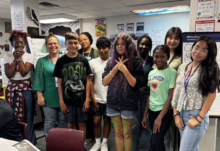 eight students with two teachers standing in classroom 