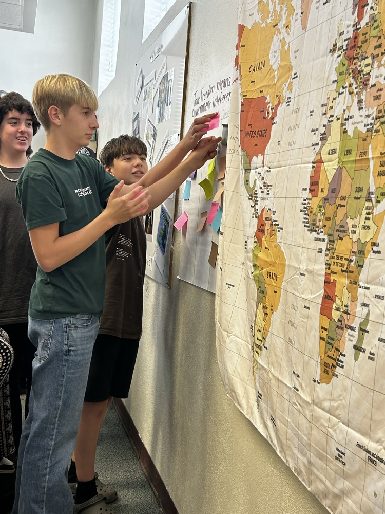 students sticking notes on poster on history class
