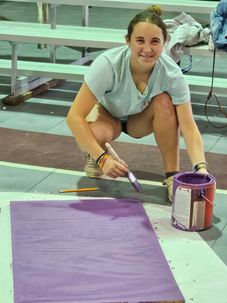female student painting wood purple