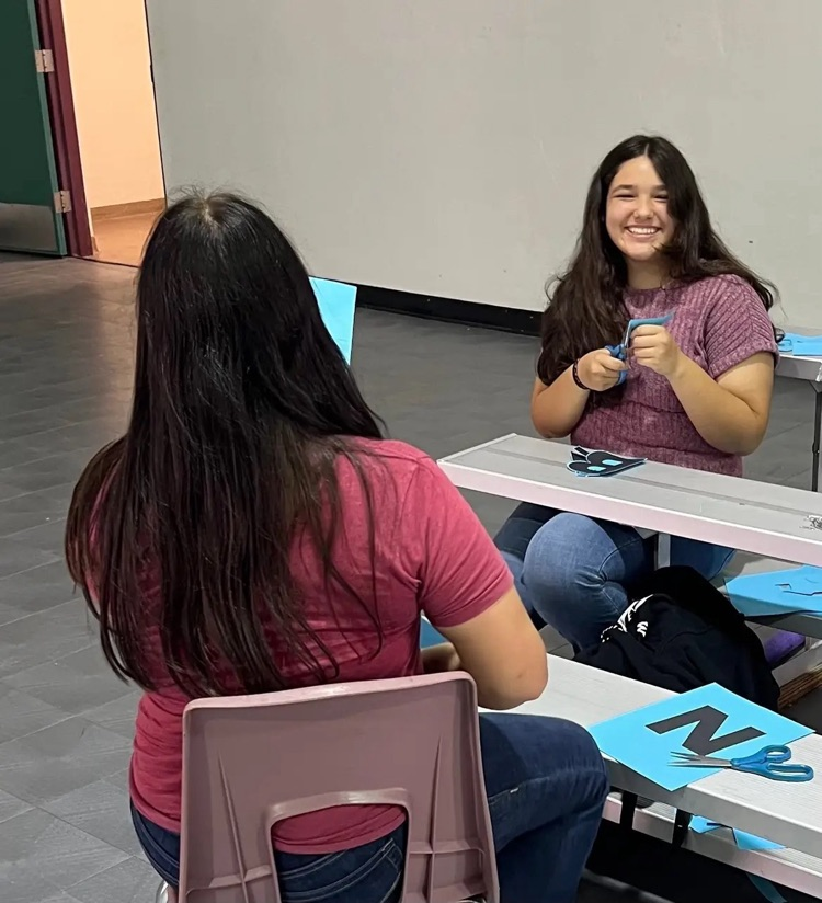 two students sitting working on accessories for homecoming float