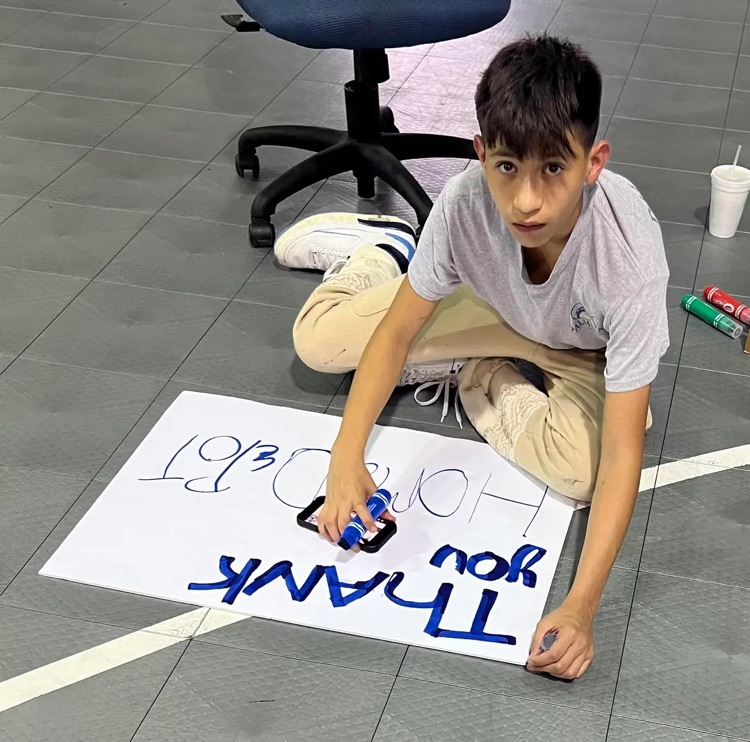 student painting thank you poster in gym floor