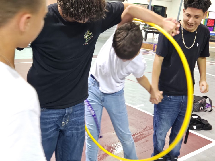 four boys playing hula hoop game in gym