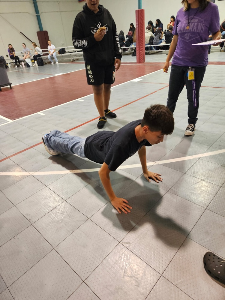 people watching kid doing push ups in gym 