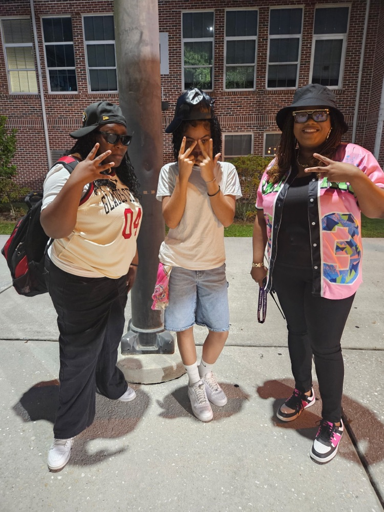 two students and assistant principal in courtyard dressed for homecoming