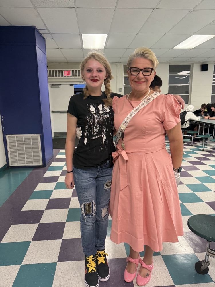 teacher and student dressed for homecoming inside cafeteria