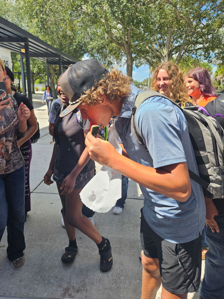 student eating watermelon for homecoming game outside Infront of students