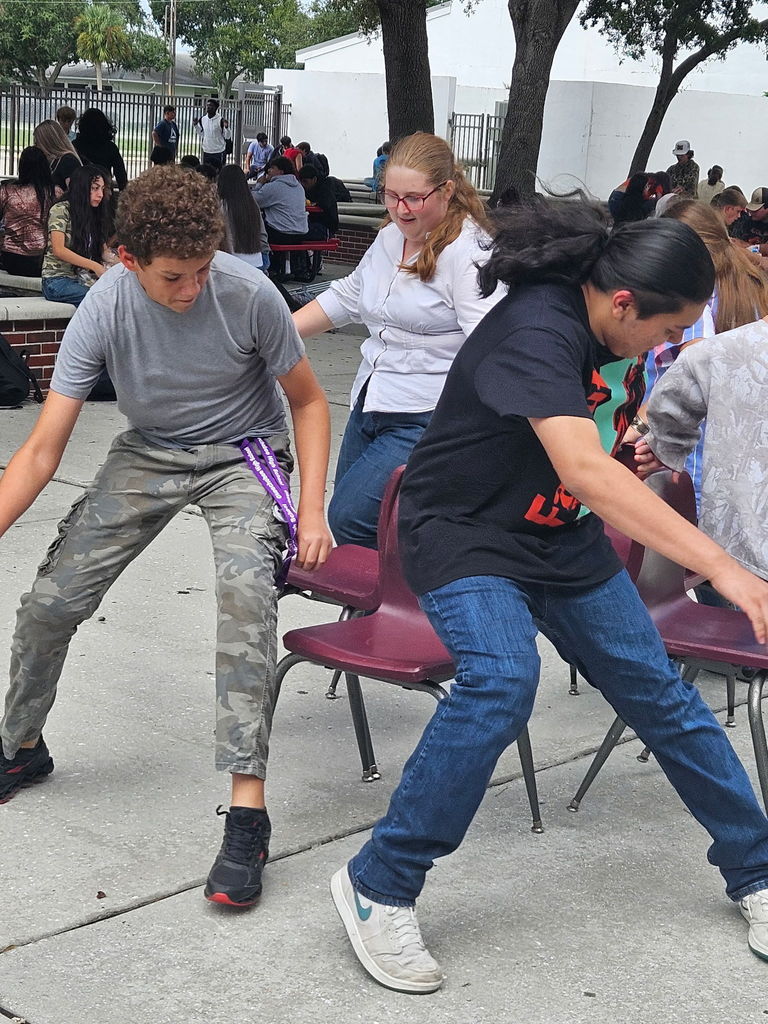 six students playing musical chairs outside at lunch courtyard