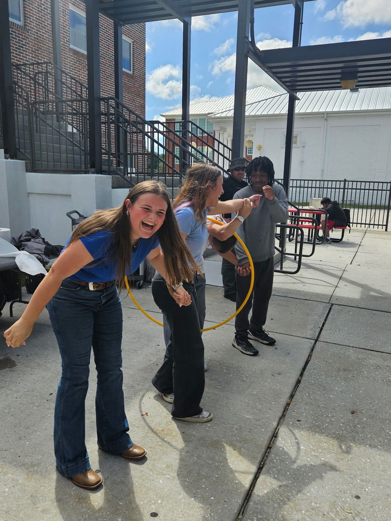 three students playing hula hoop homecoming game at lunch