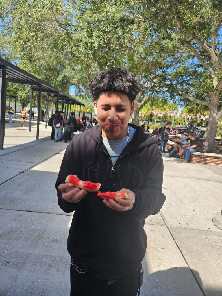 student with eyes closed and mouth full of watermelon for homecoming game