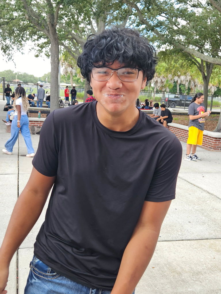 student smiling with mouth full of doughnuts