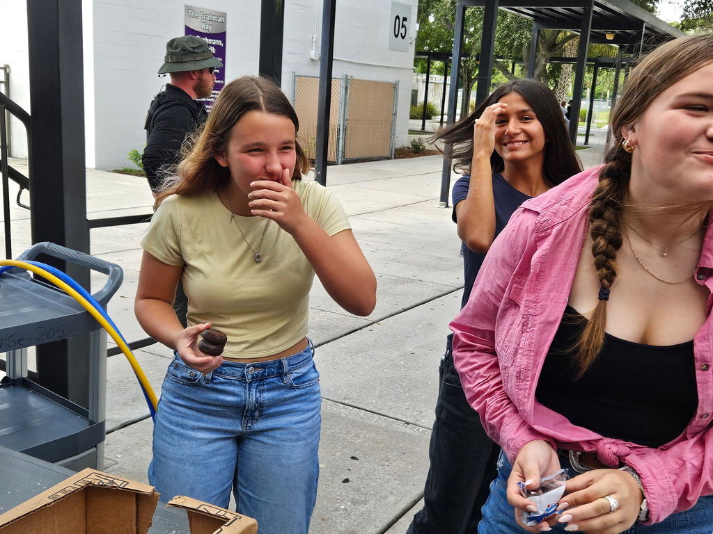 three girls laughing and covering their mouth outside in school courtyard
