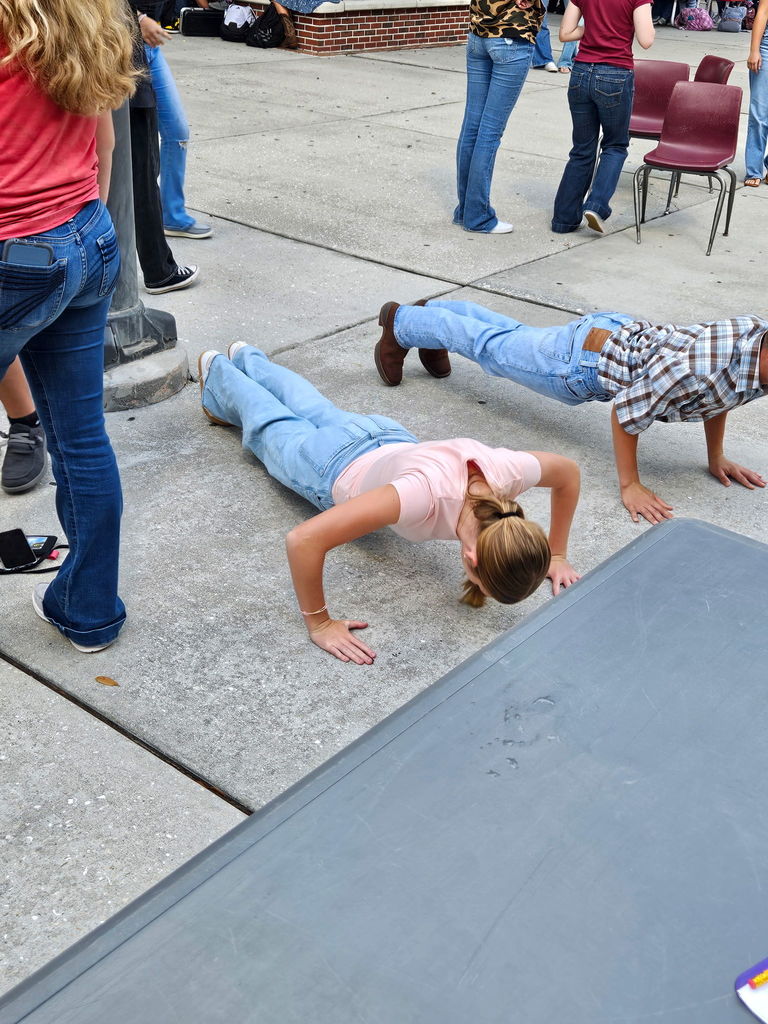 two students doing push ups at school courtyard