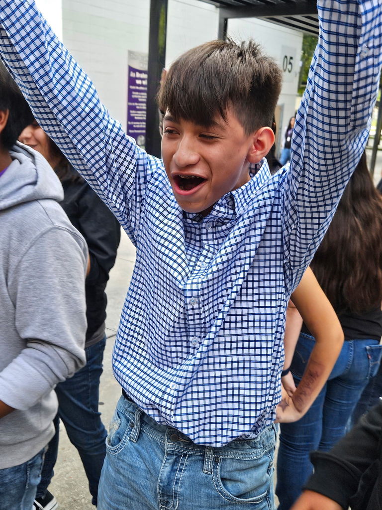 student raising his hands happy at school courtyard