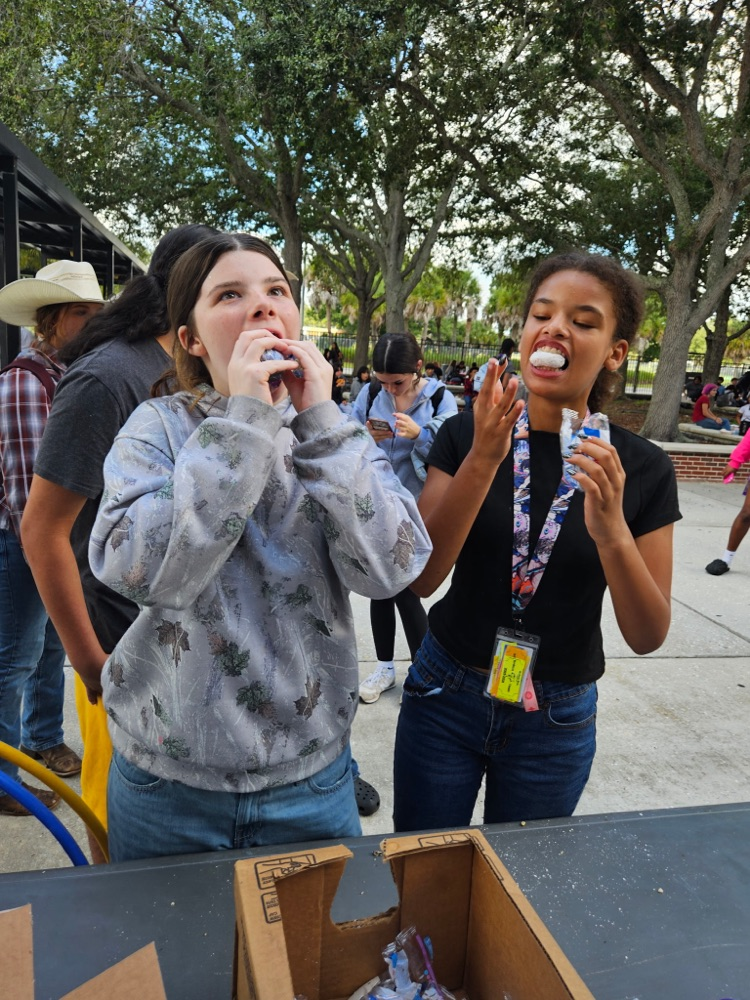 Two girls eating doughnuts at homecoming games