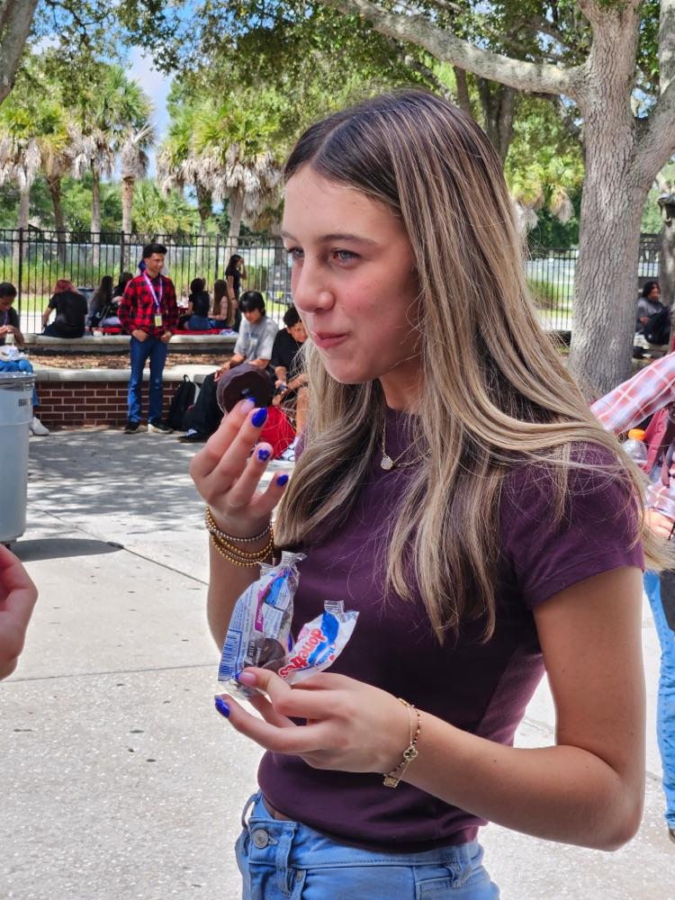 girl eating doughnuts outside school courtyard 