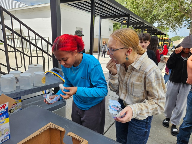Two girls stuffing their mouth with doughnuts 