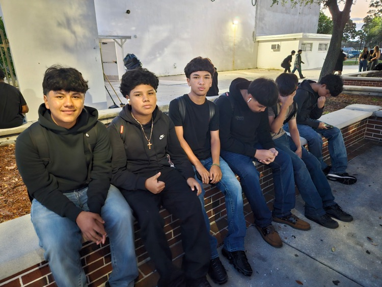 boys wearing black sitting in school courtyard 