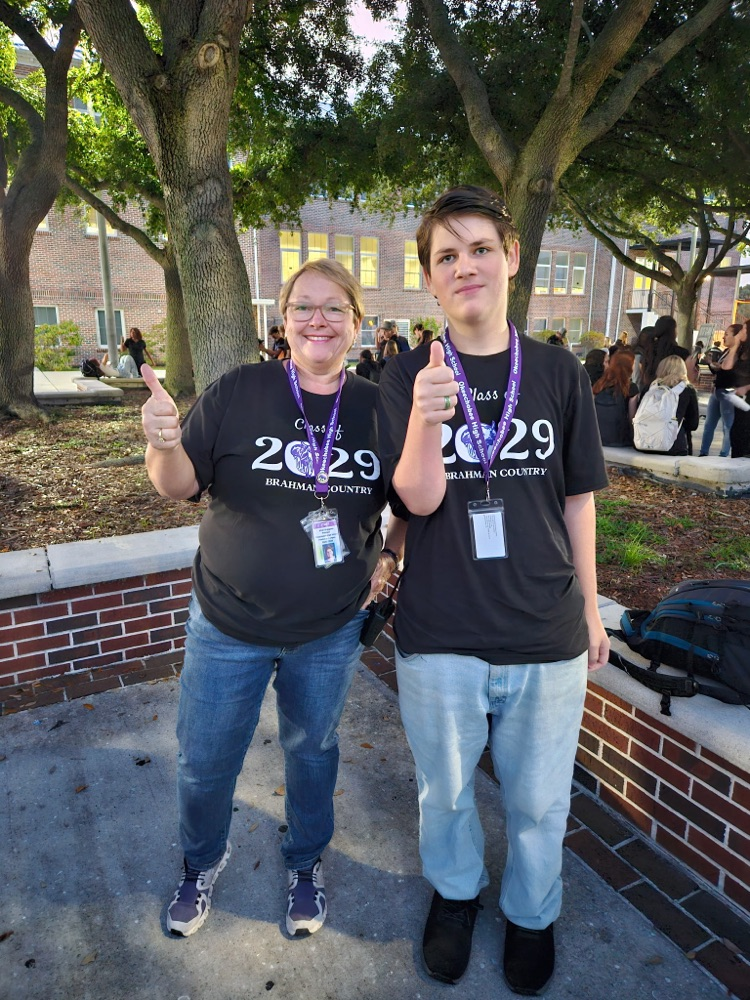 principal and Student wearing black standing in school courtyard 