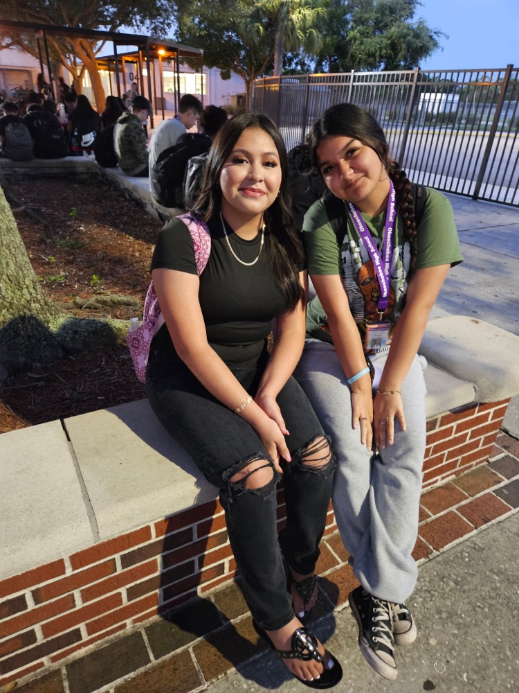Two girls wearing black sitting in school courtyard 