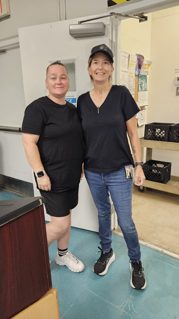 Two cafetería ladies standing in cafeteria wearing black 