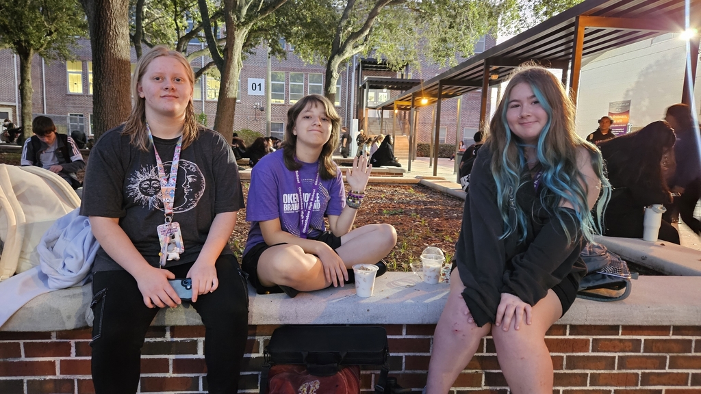 three girls sitting in school courtyard early in the morning