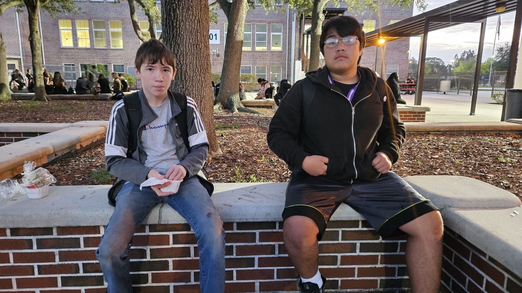 two students sitting in courtyard early in the morning
