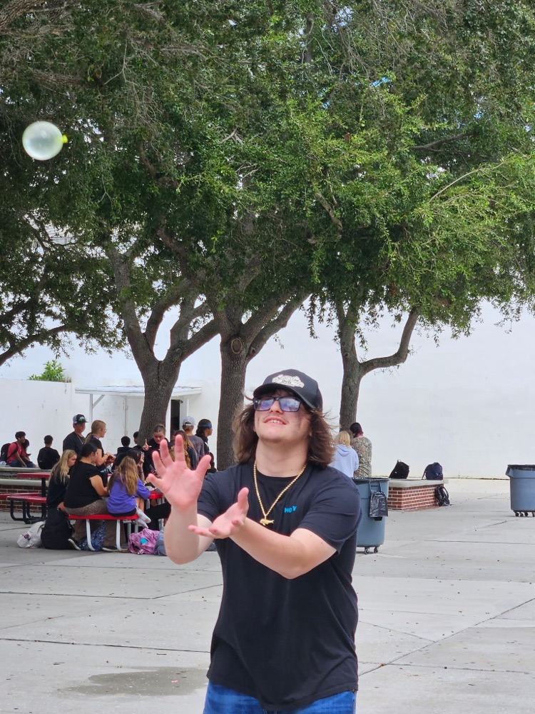 student playing water balloon game at  courtyard