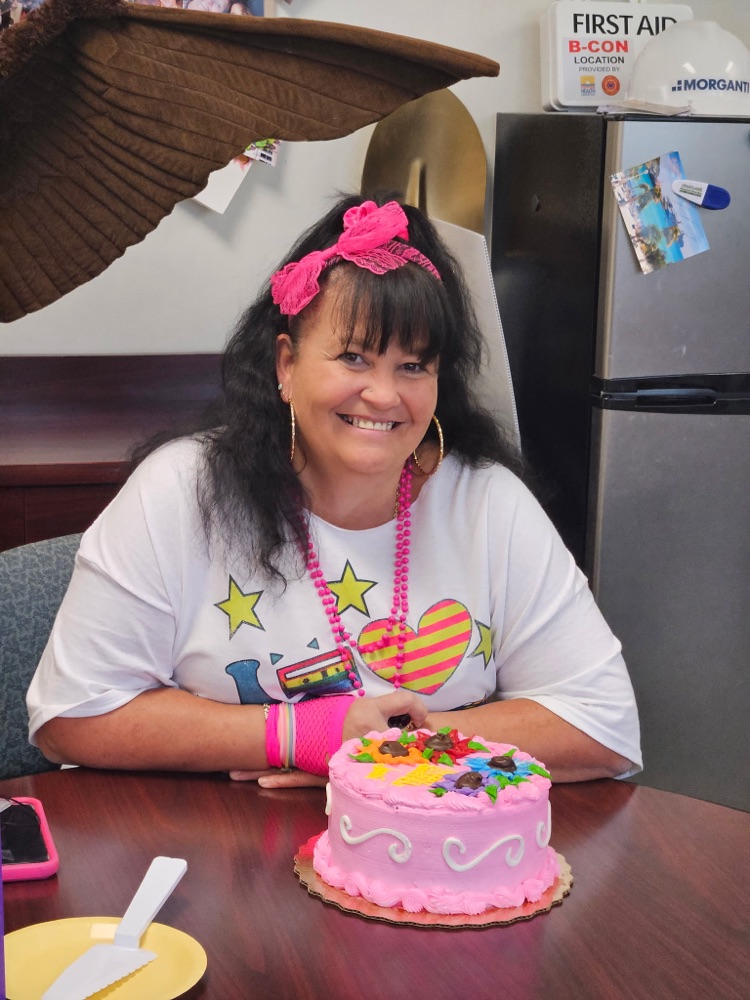 nurse aid dressed in 80s for homecoming infront of birthday cake
