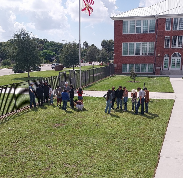 students doing science project by flagpole 