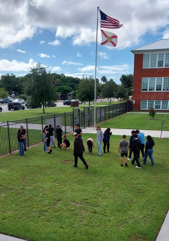 students doing science project by flagpole 